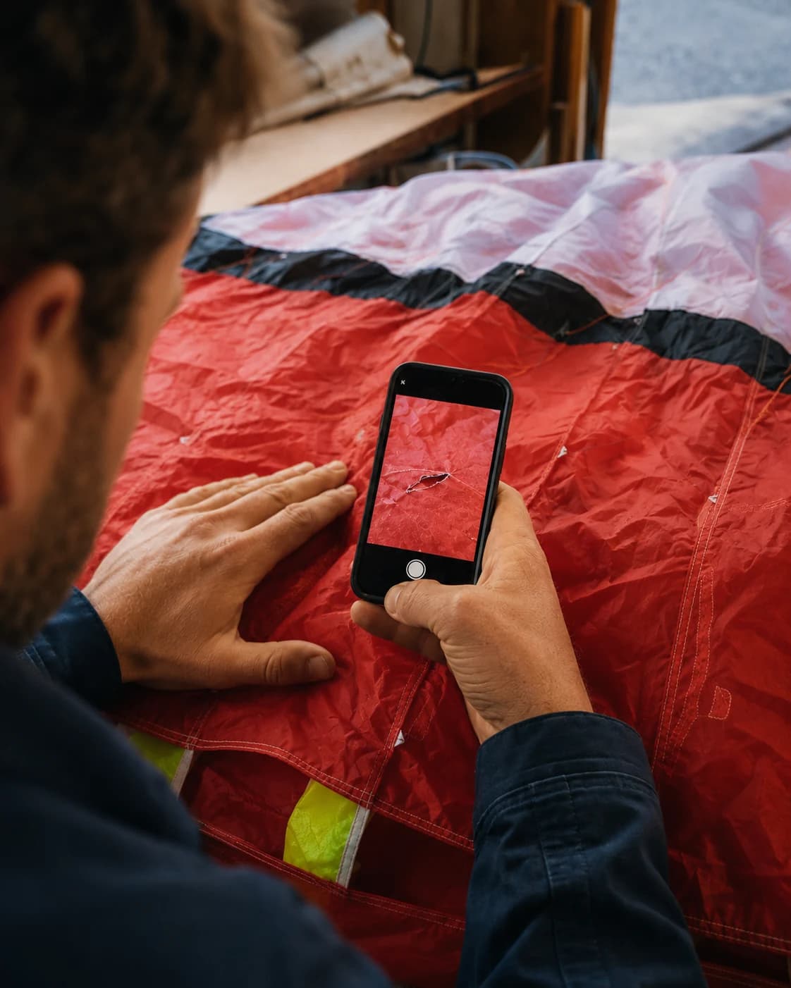 A person uses a phone to photograph a tear in canopy fabric.